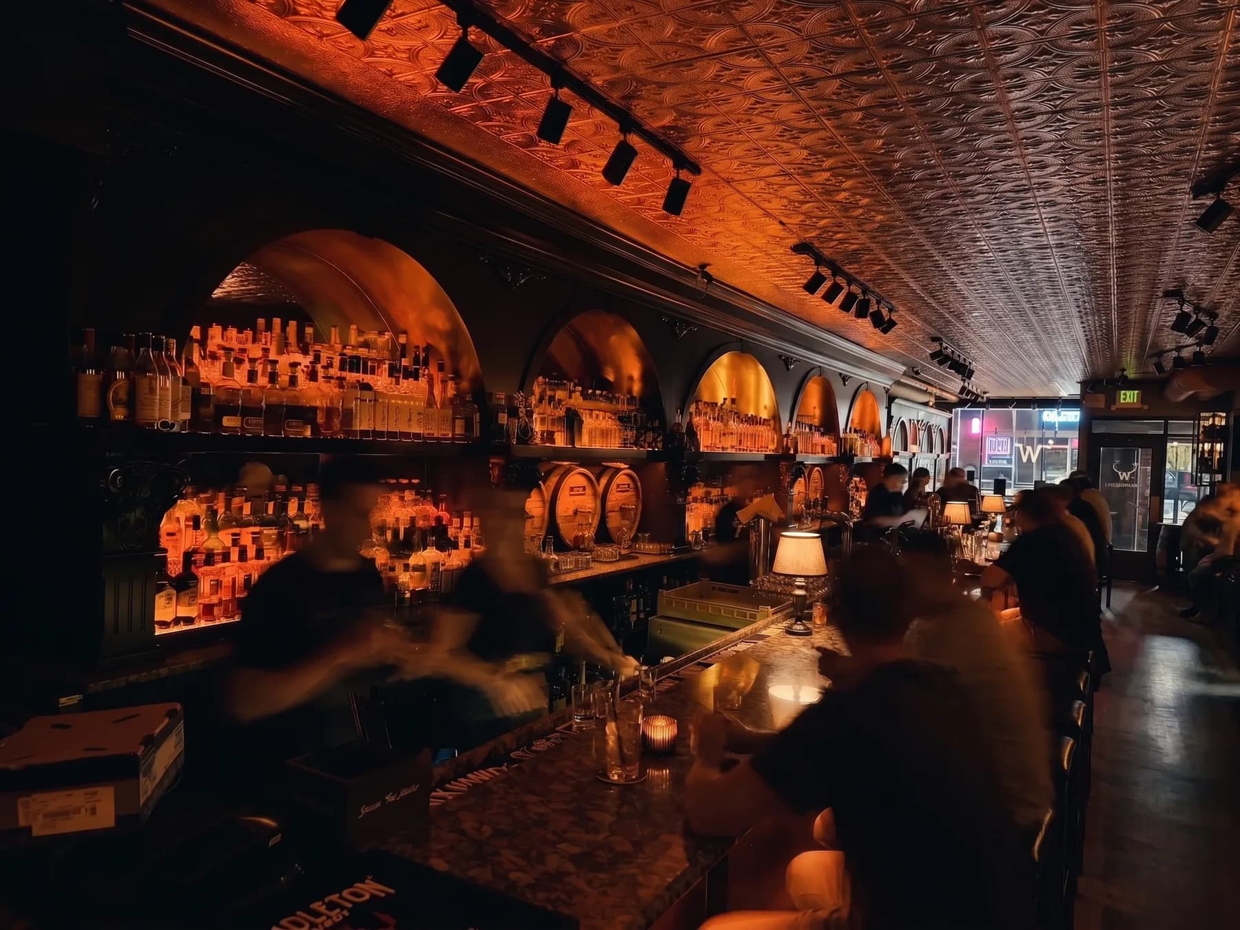 The Whisk(e)y's long bar under amber light, backbar arches full of bottles