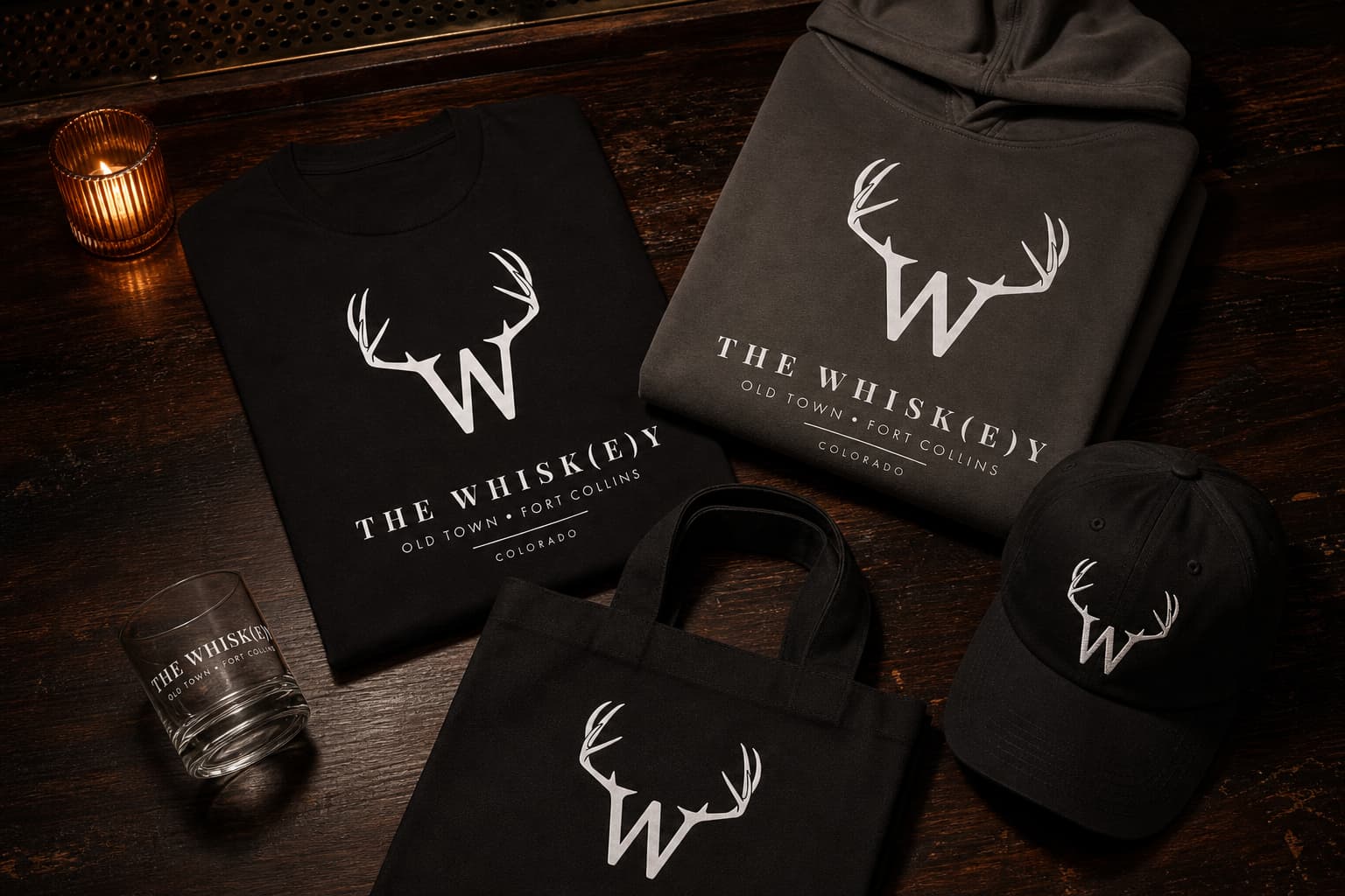 The tee, hoodie, cap, tote, and rocks glass arranged as one coordinated collection